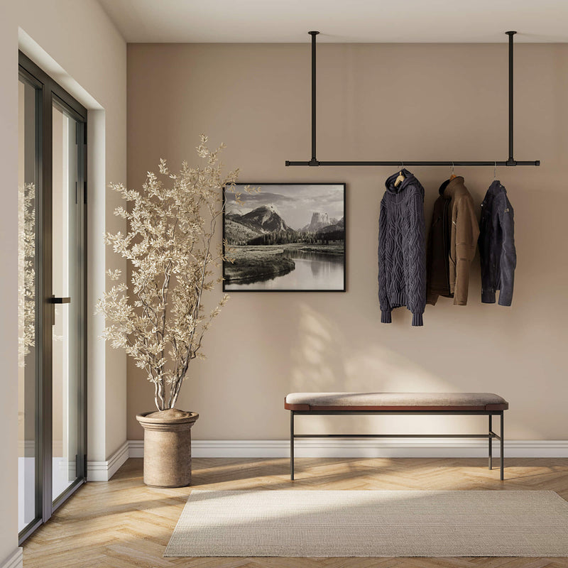 ceiling mounted clothes rail made from dark iron pipes to hang jackets in the entrance area modern design